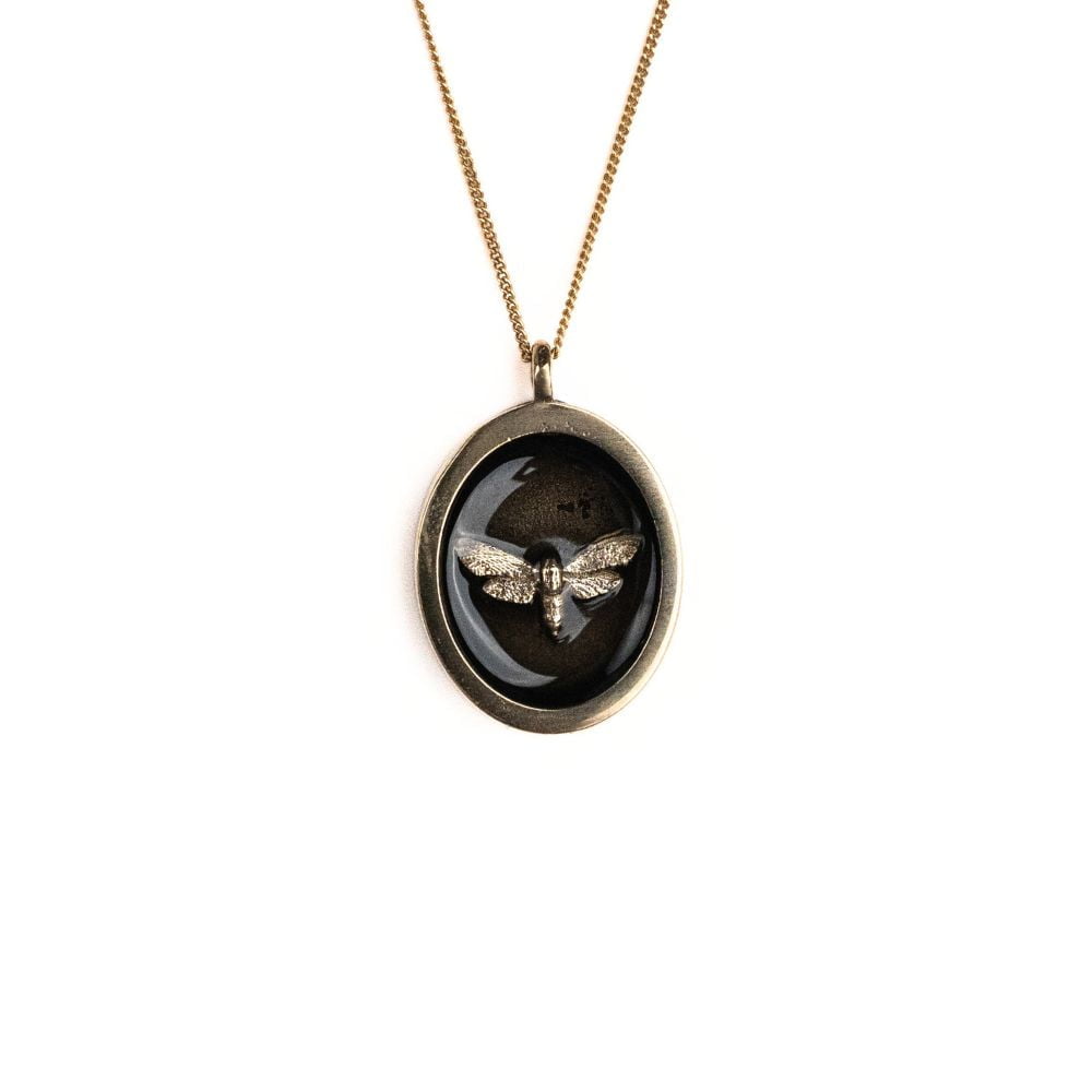 Oval brass moth pendant necklace on a gold plated sterling silver chain.