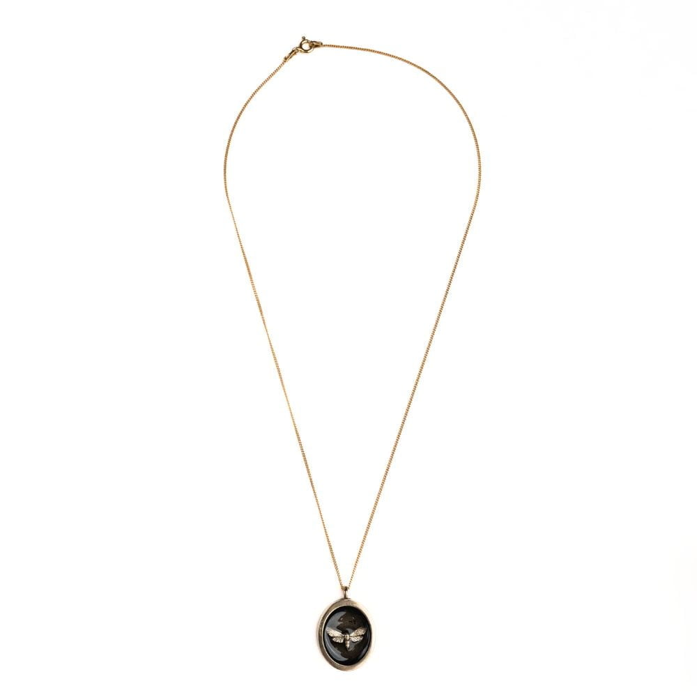 Oval brass moth pendant necklace on a gold plated sterling silver chain.