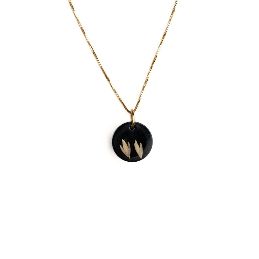 Gold plated sterling silver necklace with black resin pendant featuring real grass seeds from Cape Town.