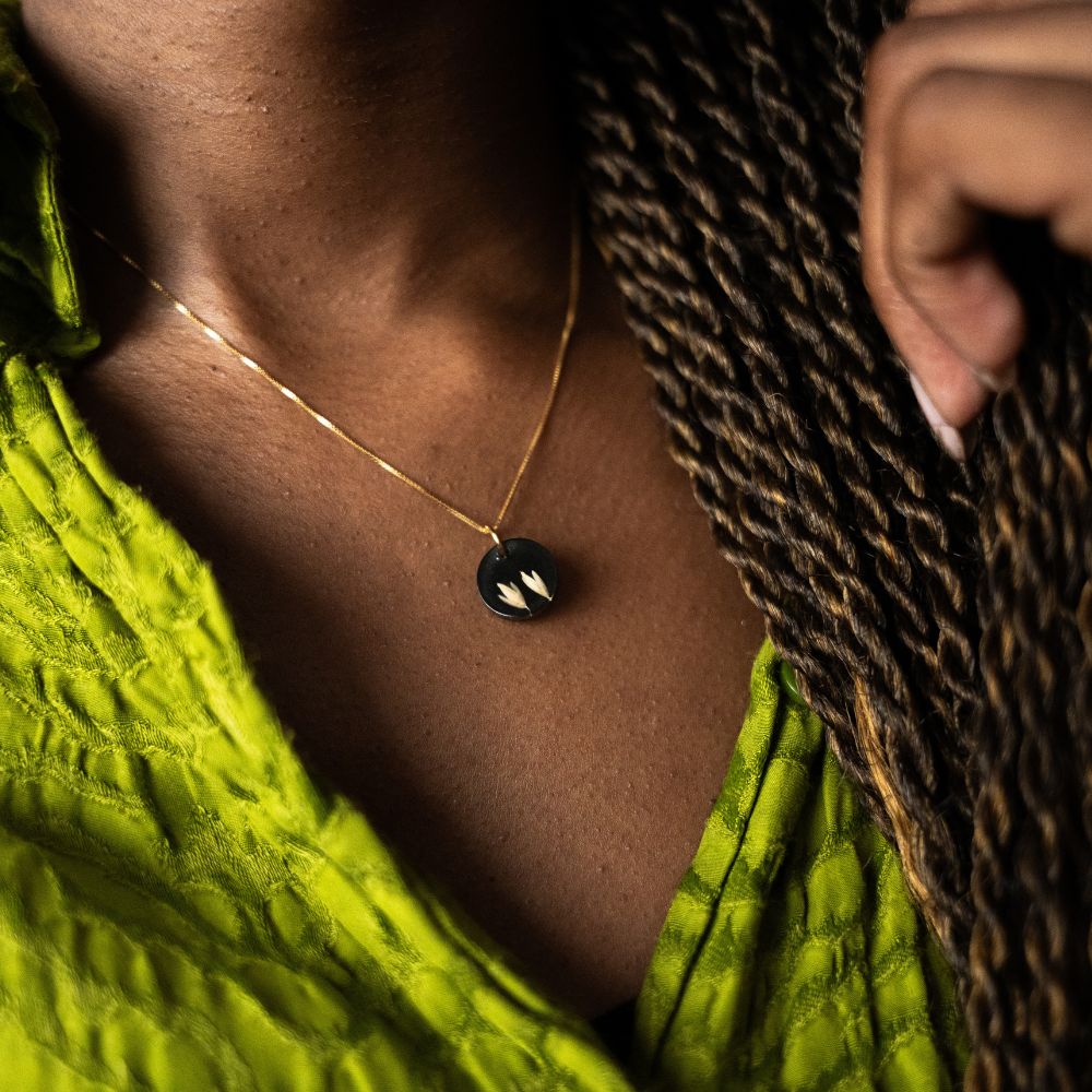 Gold plated sterling silver necklace with black resin pendant featuring real grass seeds from Cape Town.