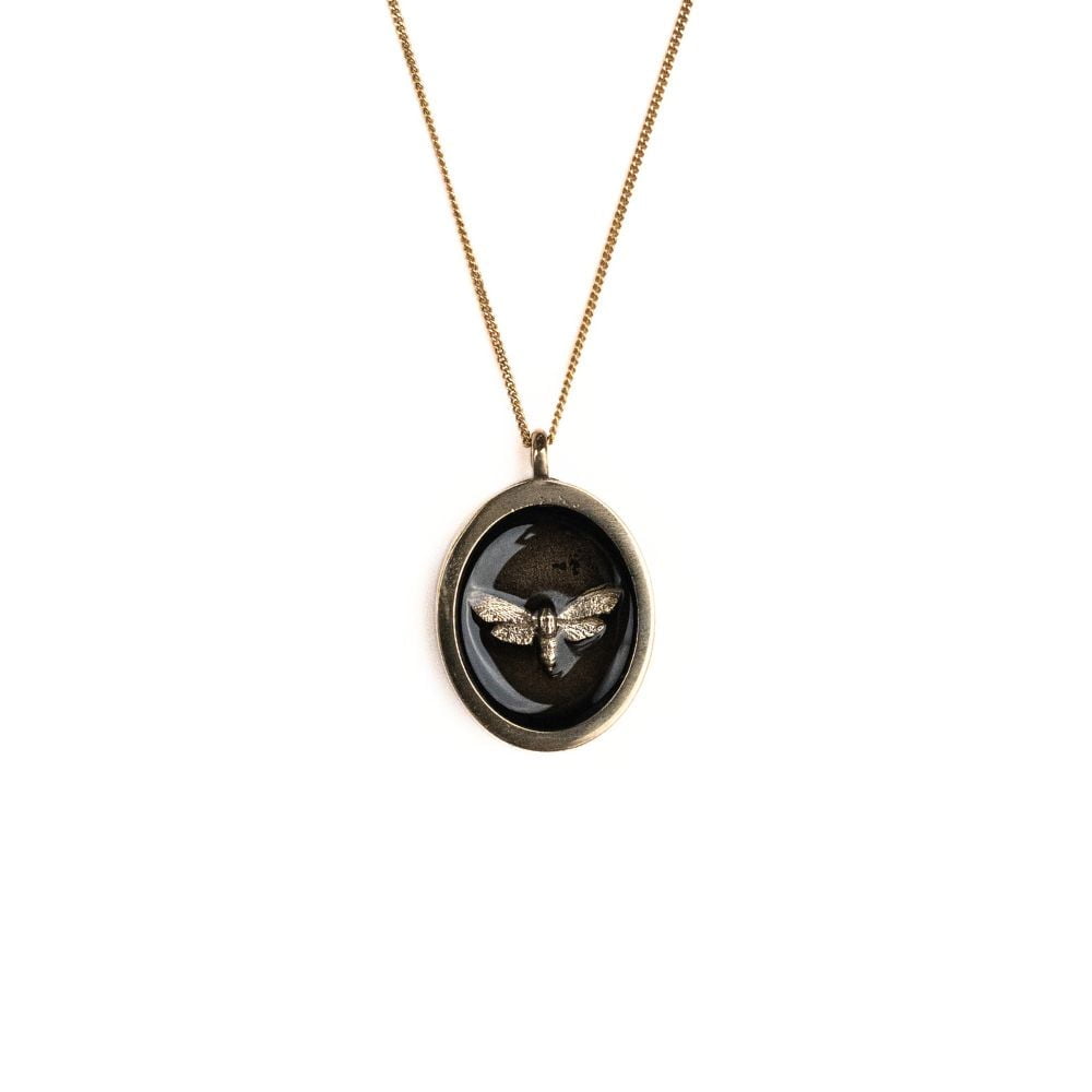Oval brass moth pendant necklace on a gold plated sterling silver chain.