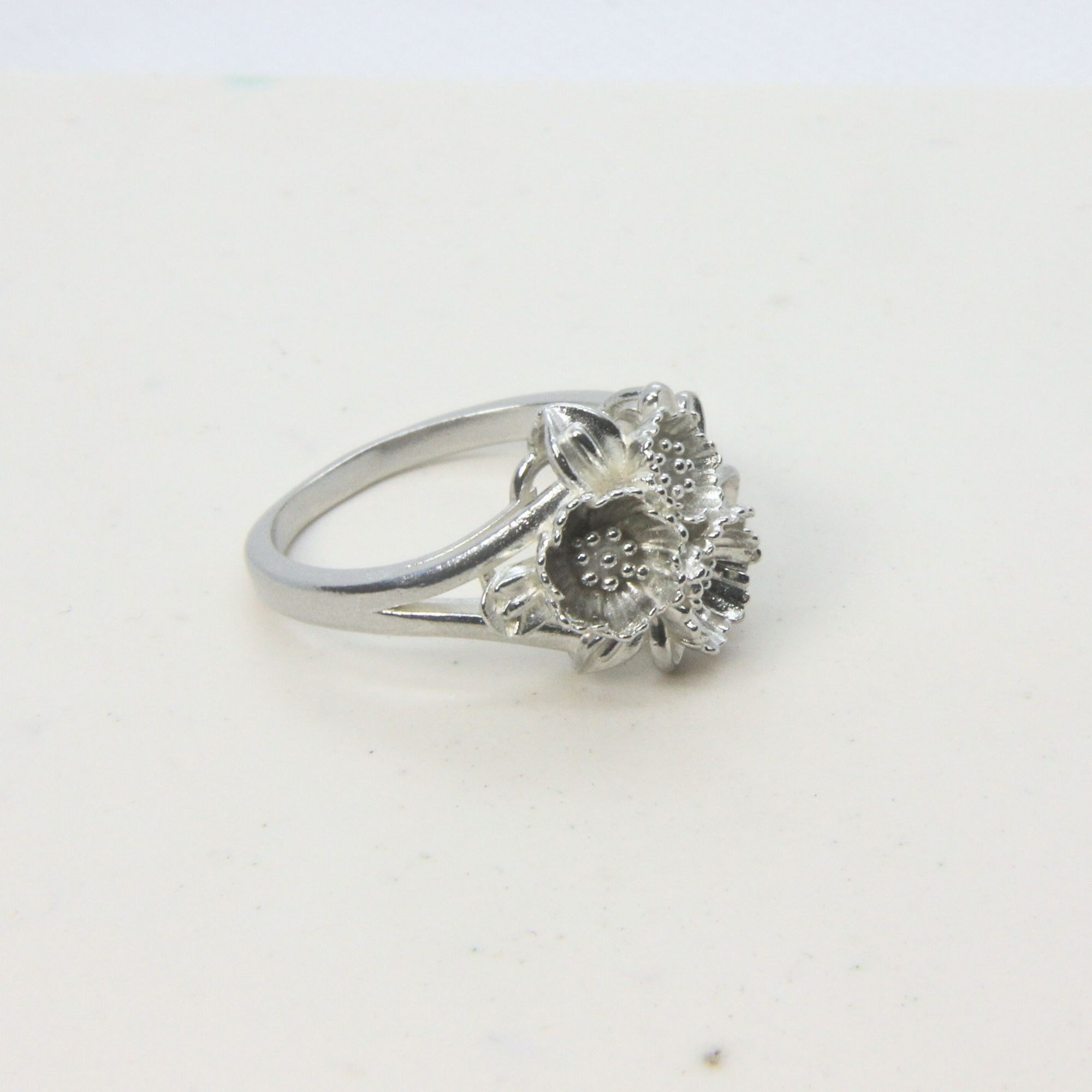 Sterling silver ring featuring a cluster of small floral forms with textured centres.