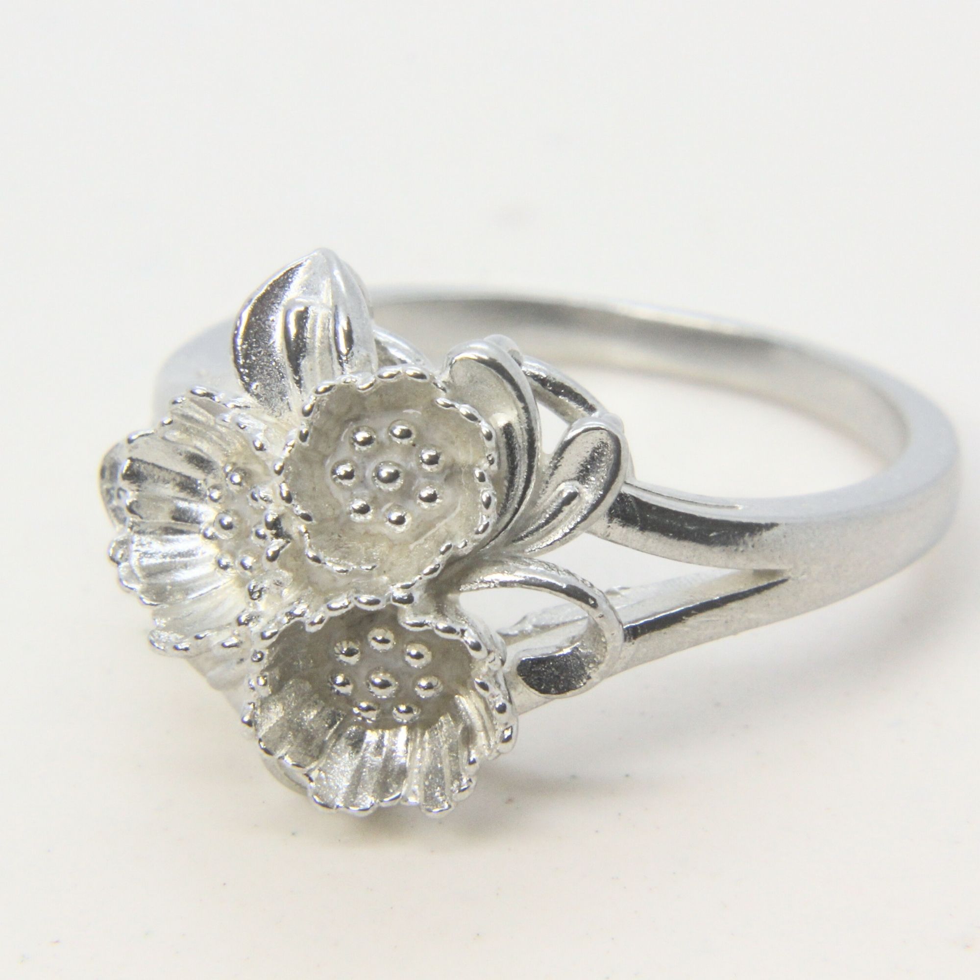 Sterling silver ring featuring a cluster of small floral forms with textured centres.