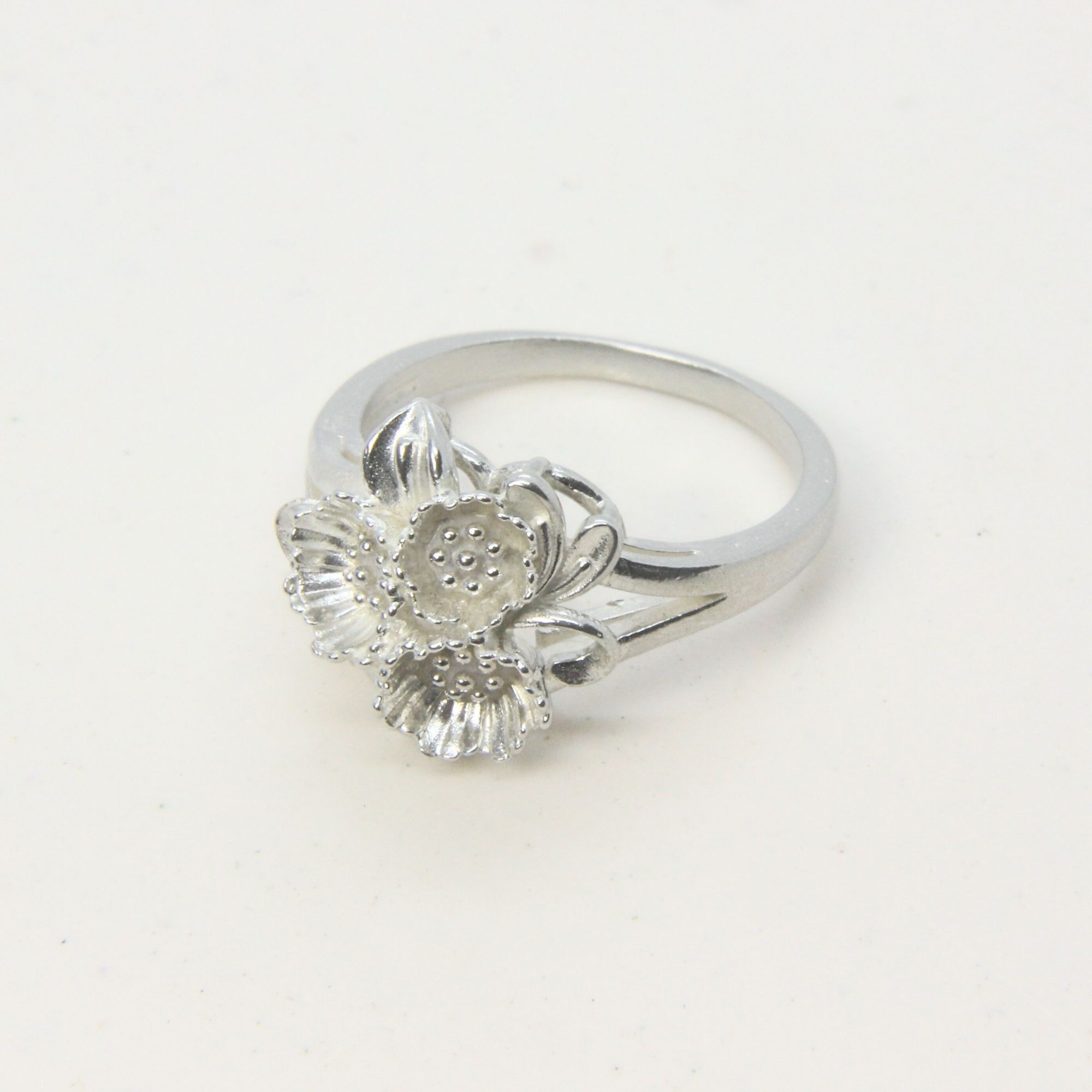Sterling silver ring featuring a cluster of small floral forms with textured centres.