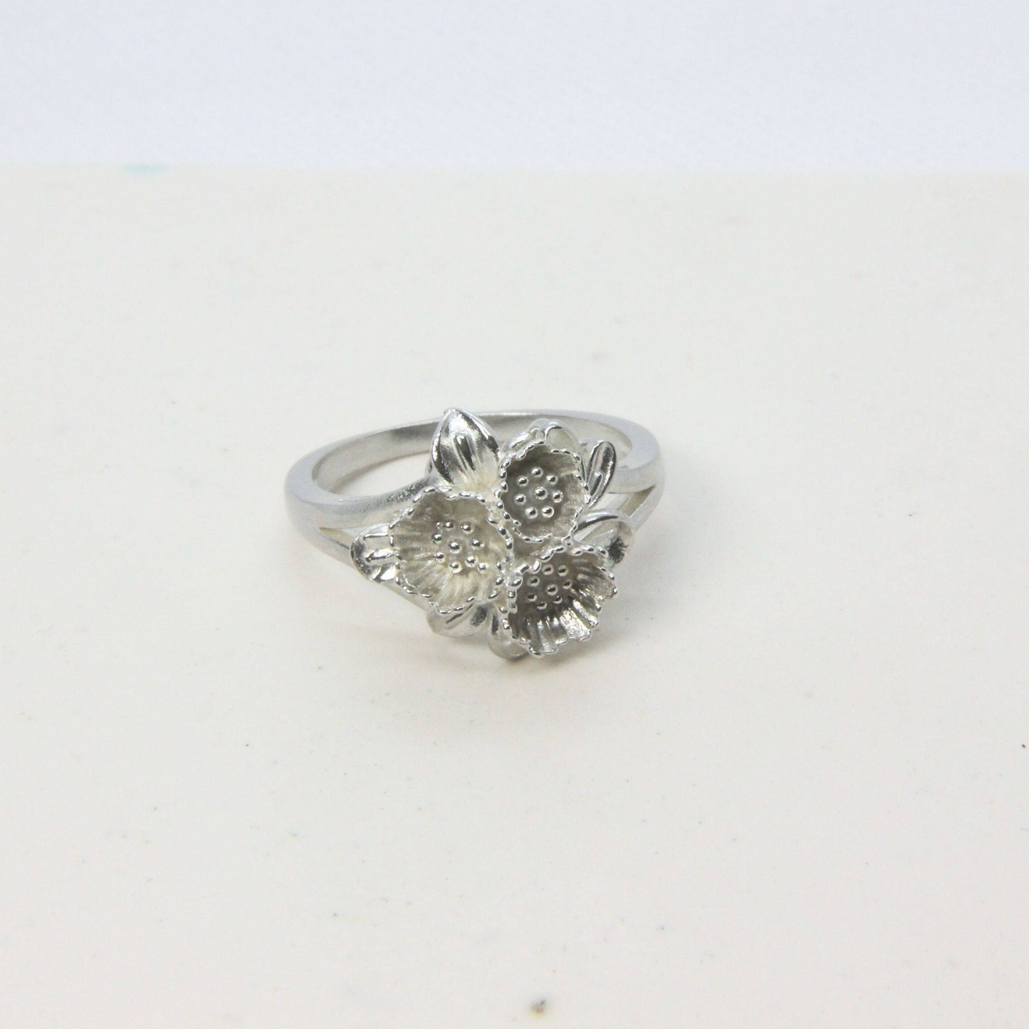 Sterling silver ring featuring a cluster of small floral forms with textured centres.