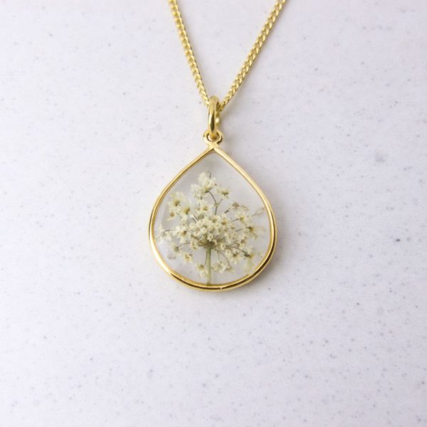 Gold teardrop pendant with preserved wild lace flowers set in clear resin on a gold chain.