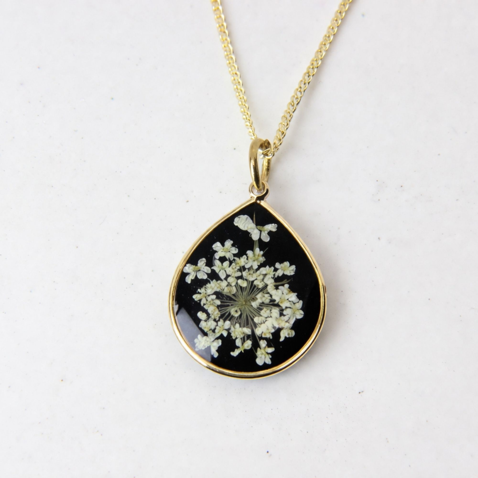 Handmade gold pendant with delicate white lace flowers on black resin base