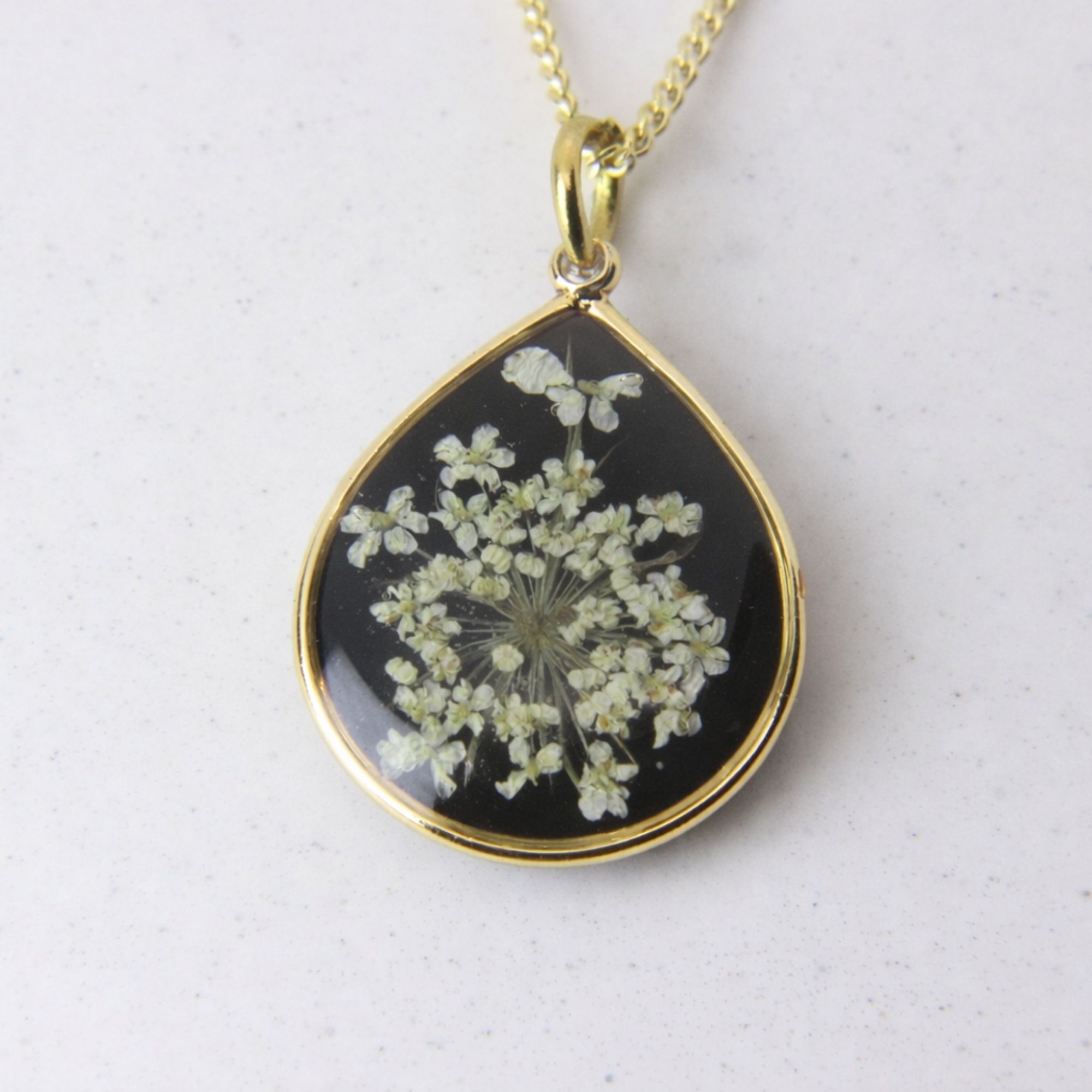 Handmade gold pendant with delicate white lace flowers on black resin base