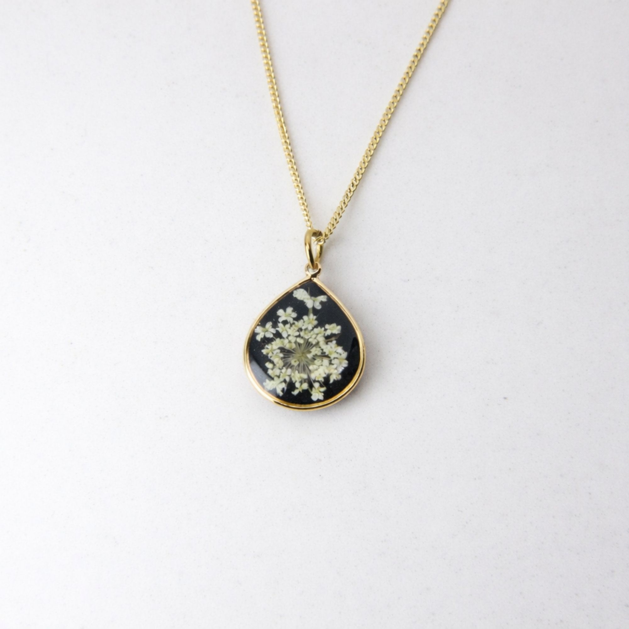 Handmade gold pendant with delicate white lace flowers on black resin base