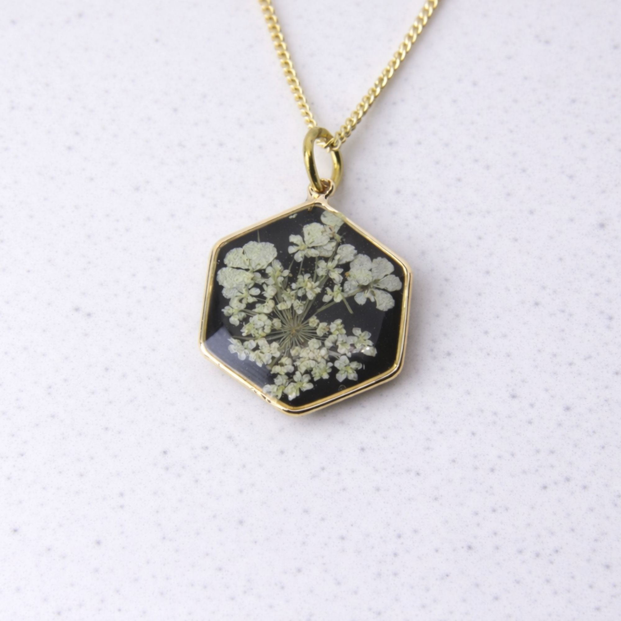 Gold hexagon pendant with wild lace flowers set in black resin.