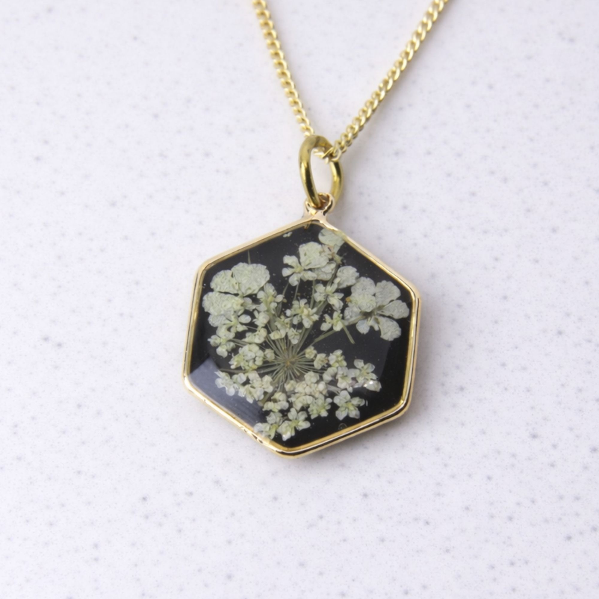 Gold hexagon pendant with wild lace flowers set in black resin.