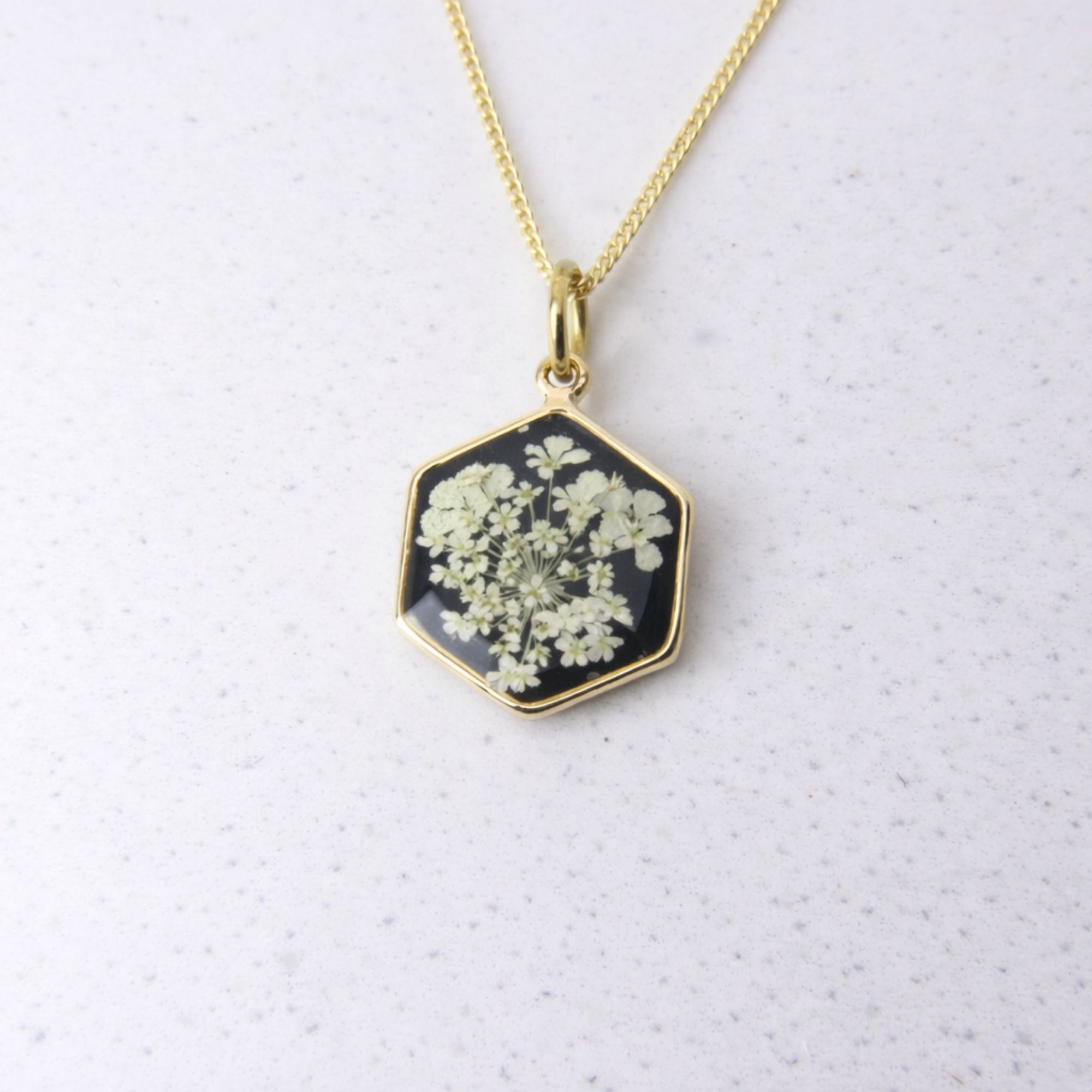 Gold hexagon pendant with wild lace flowers set in black resin.