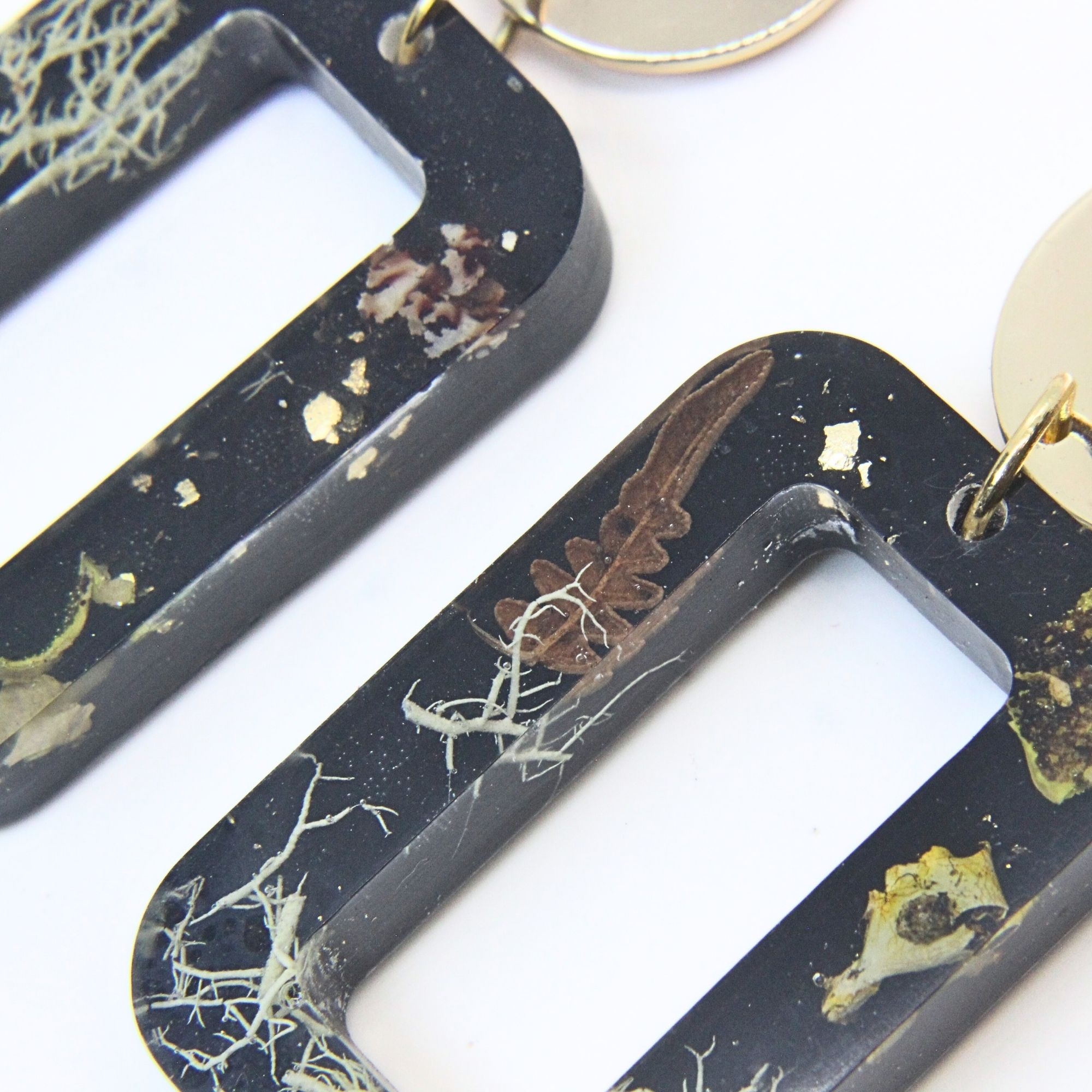 Black rectangular resin earrings with wild lichen, fern and moss inlay, gold plated brass disc tops and sterling silver studs.