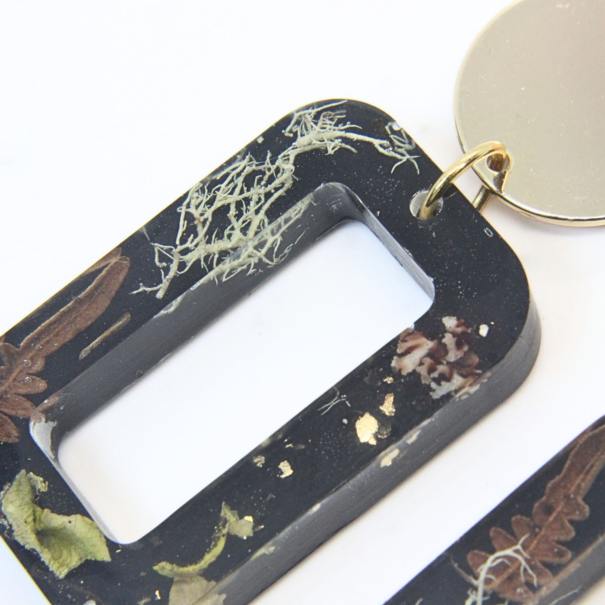 Black rectangular resin earrings with wild lichen, fern and moss inlay, gold plated brass disc tops and sterling silver studs.