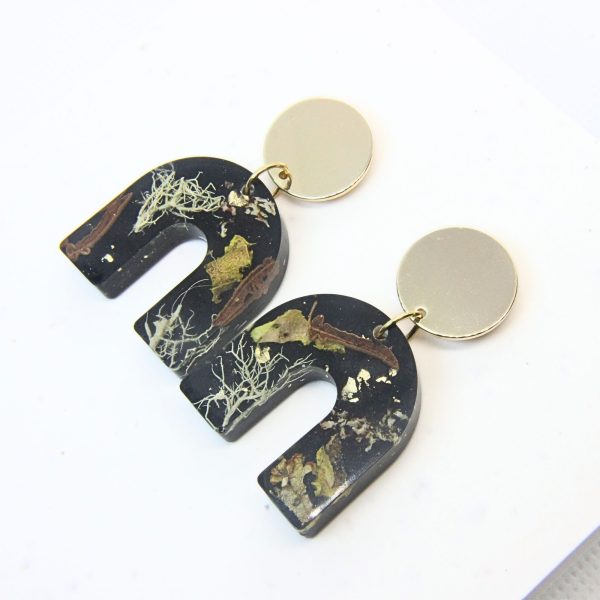 Black solid resin arch earrings with grass seed inlay and gold plated sterling silver disc tops.