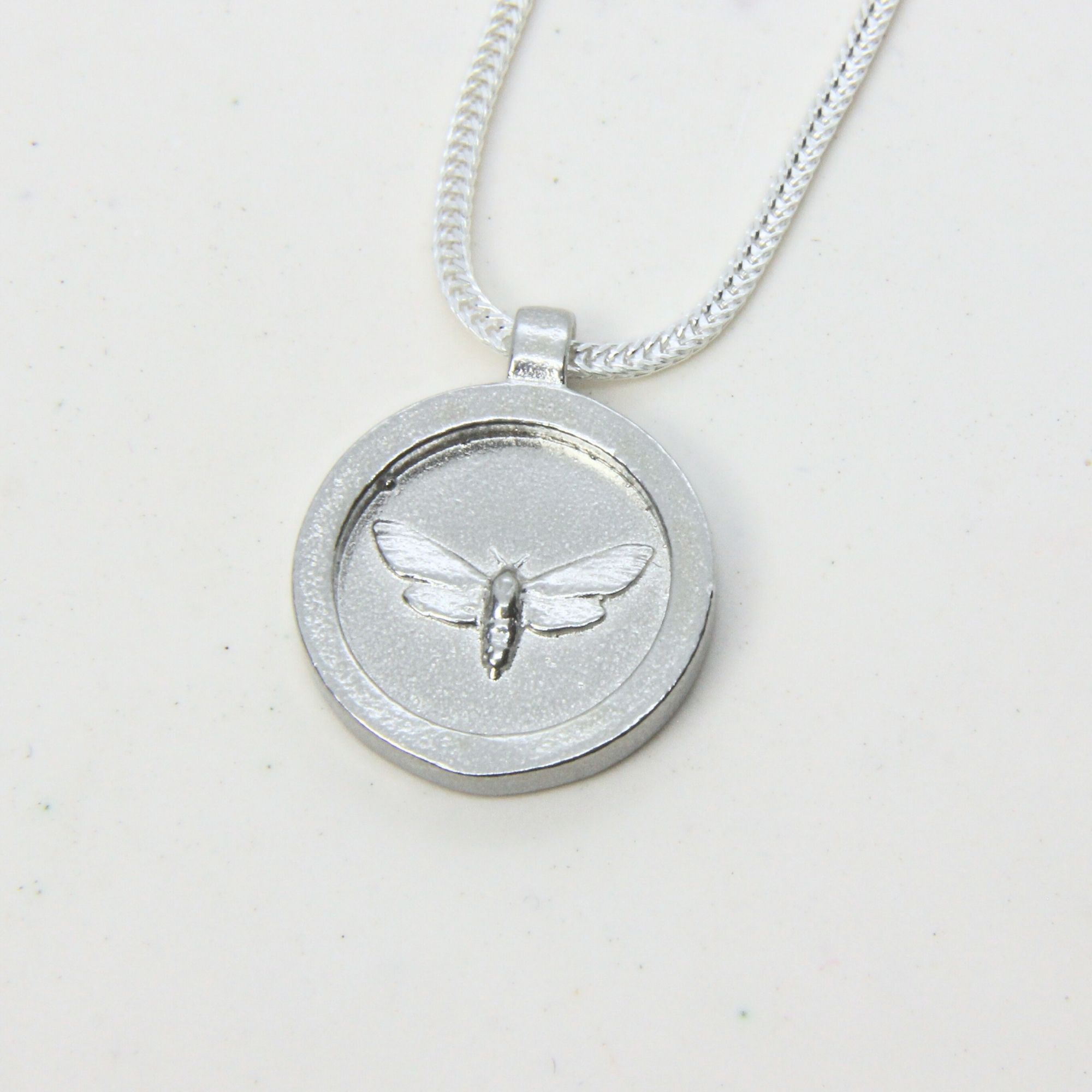 Sterling silver disc pendant engraved with a moth, on a silver chain.