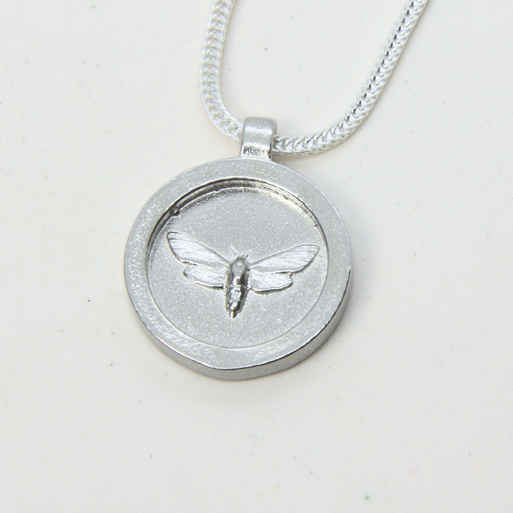 Sterling silver disc pendant engraved with a moth, on a silver chain.