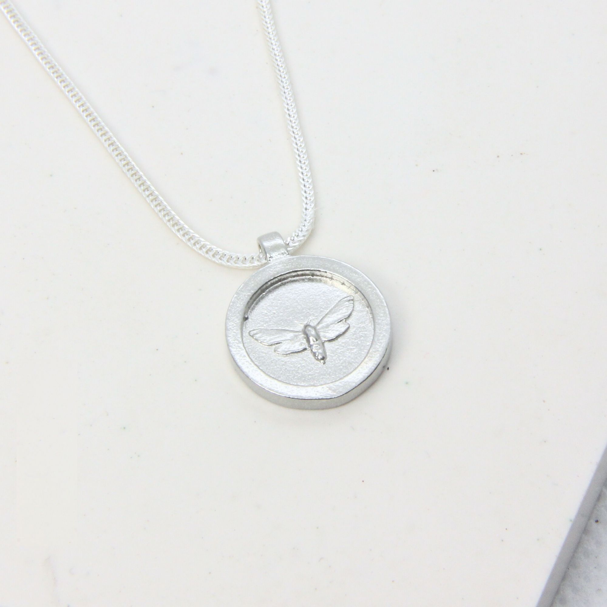 Sterling silver disc pendant engraved with a moth, on a silver chain.