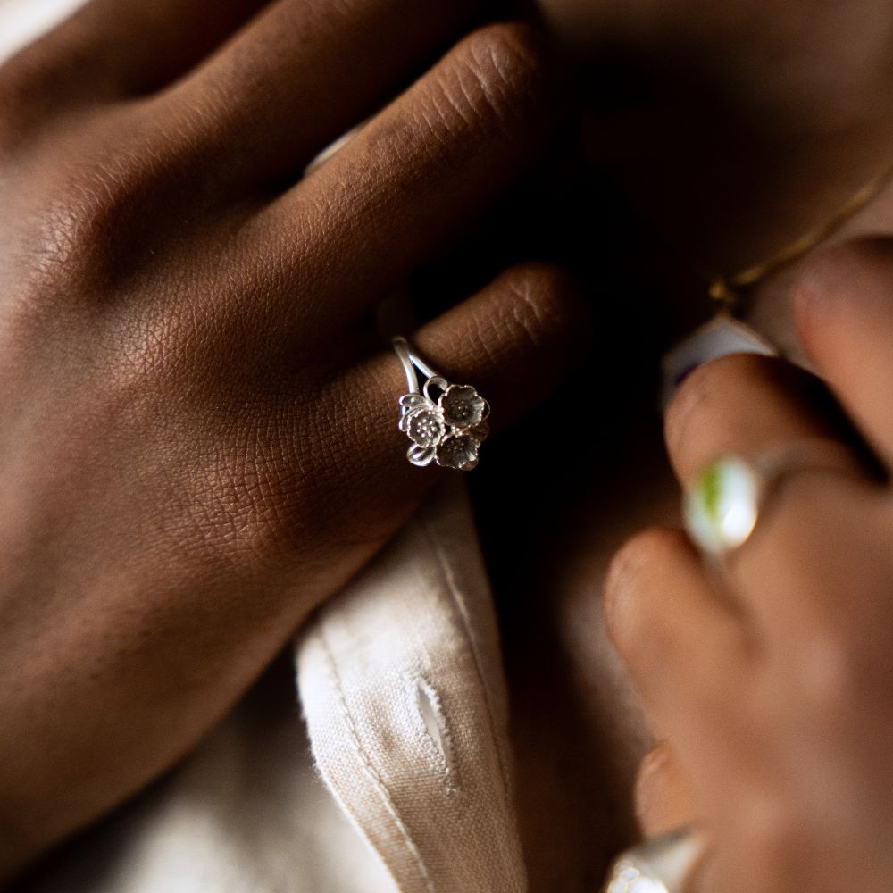 Sterling silver ring featuring a small sculpted bouquet of flowers on a slim band.