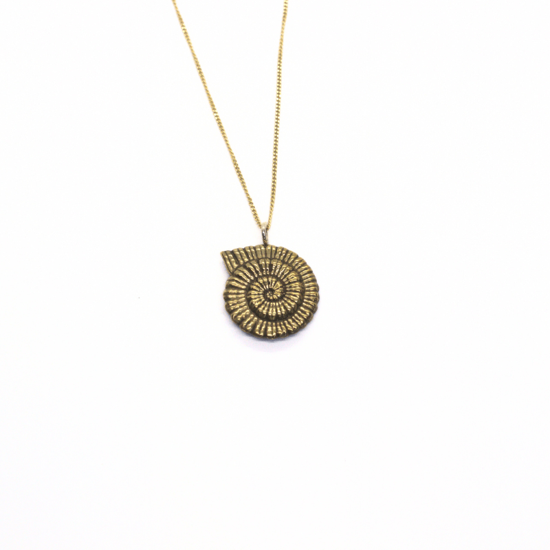 Brass ammonite pendant necklace on sterling silver chain worn layered with gold chain.