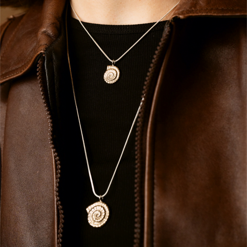 Brass ammonite pendant necklace on sterling silver chain worn layered with gold chain.