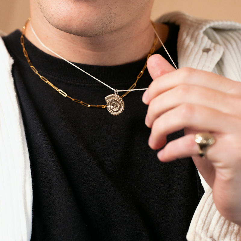 Brass ammonite pendant necklace on sterling silver chain worn layered with gold chain.