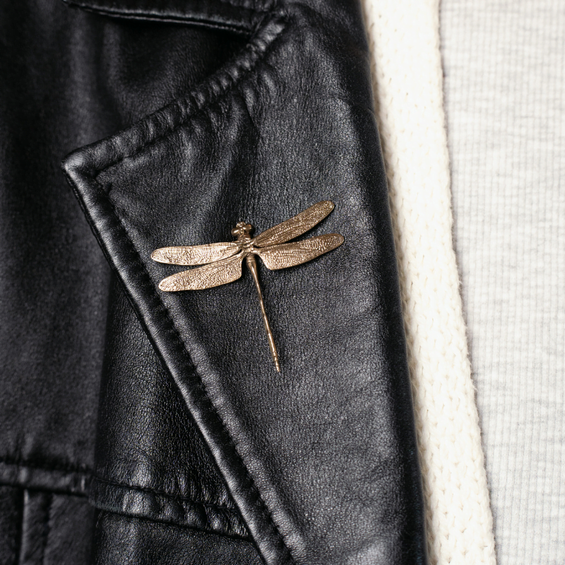 Brass dragonfly brooch featuring finely textured wings and sculpted body detail