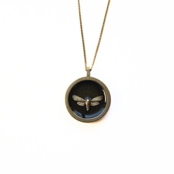 Round solid brass pendant necklace with tiny brass moth in dark resin inlay on gold plated sterling silver chain.