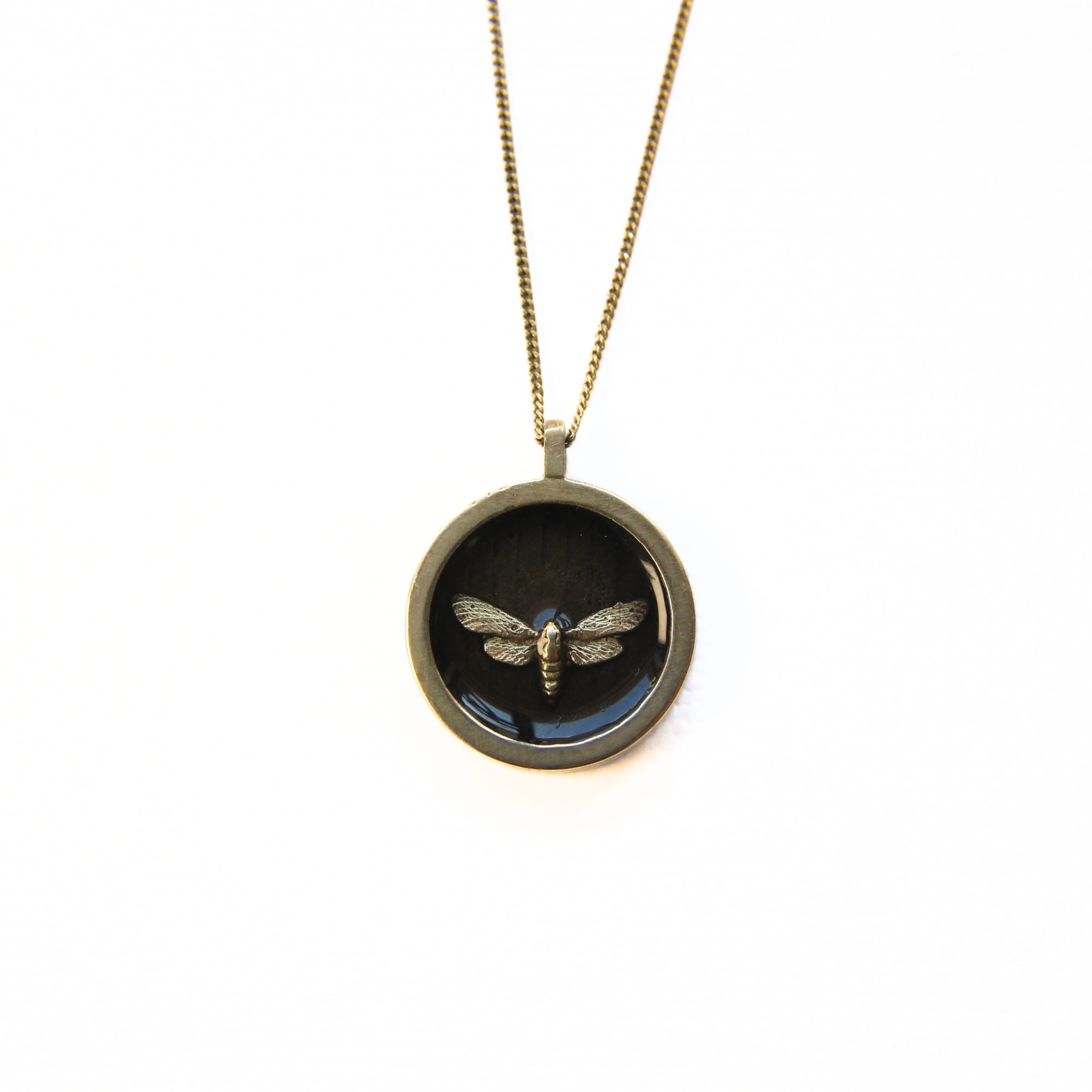 Round solid brass pendant necklace with tiny brass moth in dark resin inlay on gold plated sterling silver chain.