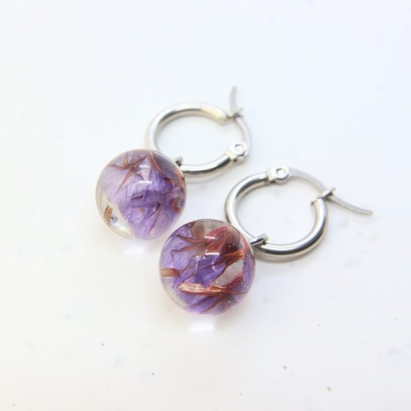 Clear resin globe hoop earring with preserved sea lavender flower and stainless steel hoop fitting.