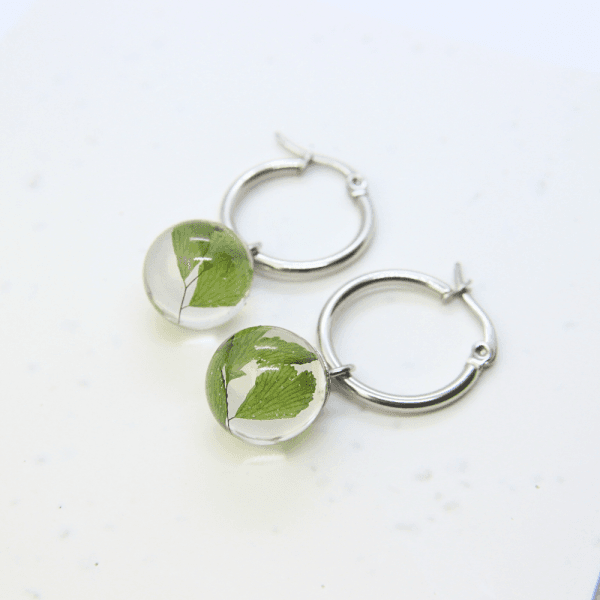 Clear resin globe hoop earring with preserved maidenhair fern, stainless steel hoop fitting.