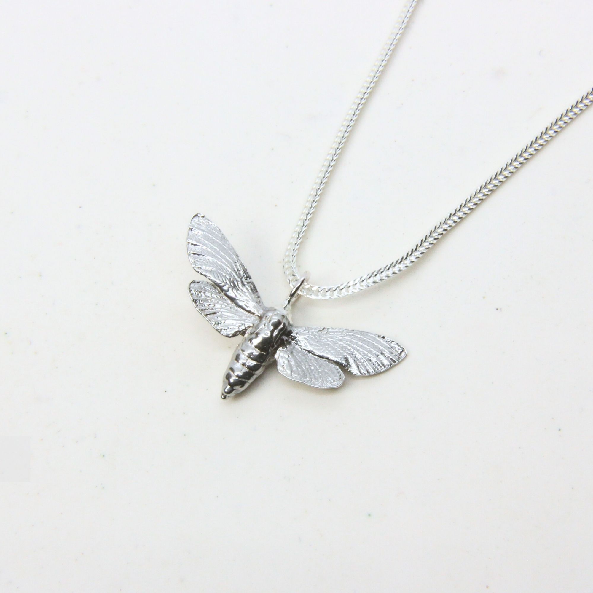 Sterling silver bee pendant with detailed wings and body on a silver chain.