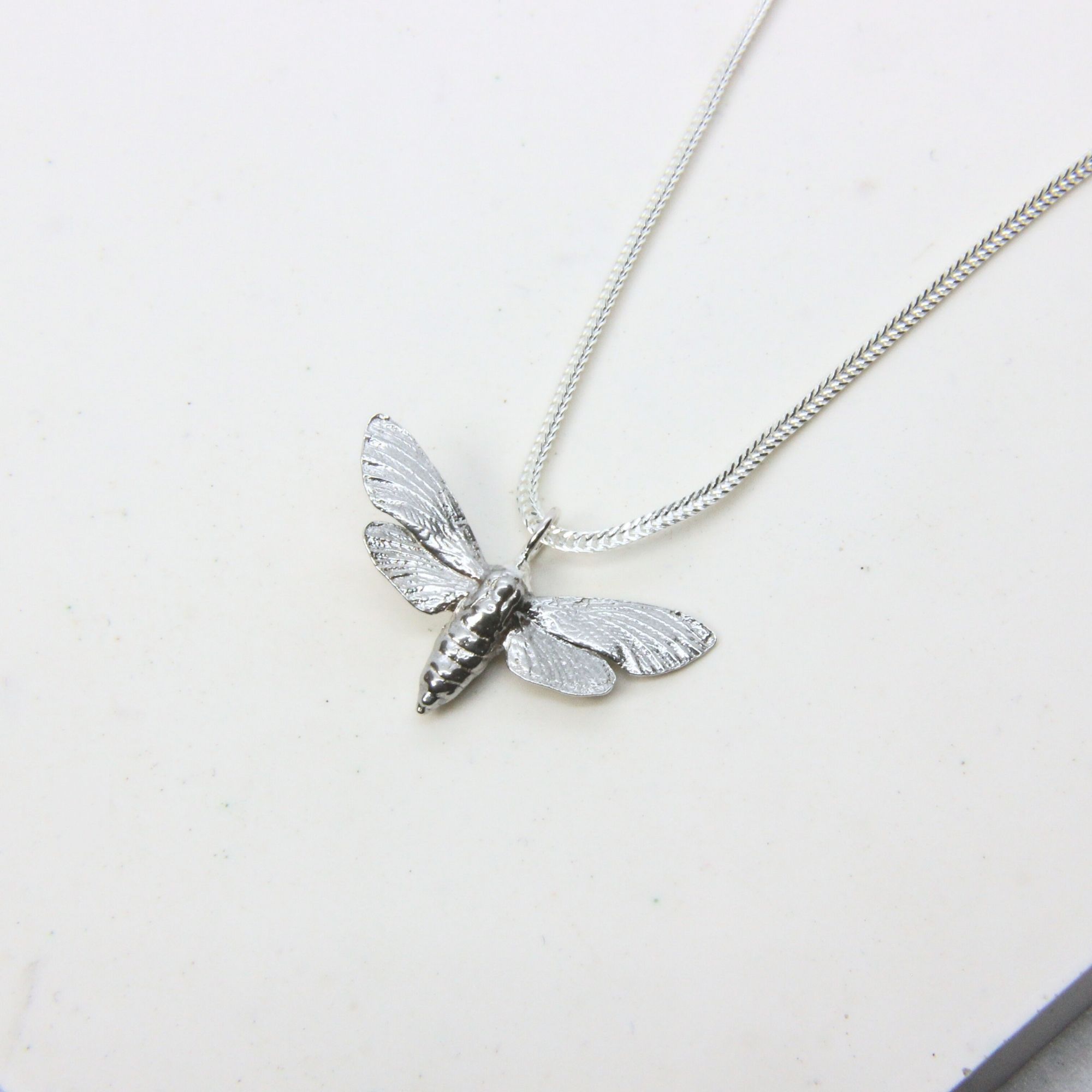 Sterling silver bee pendant with detailed wings and body on a silver chain.