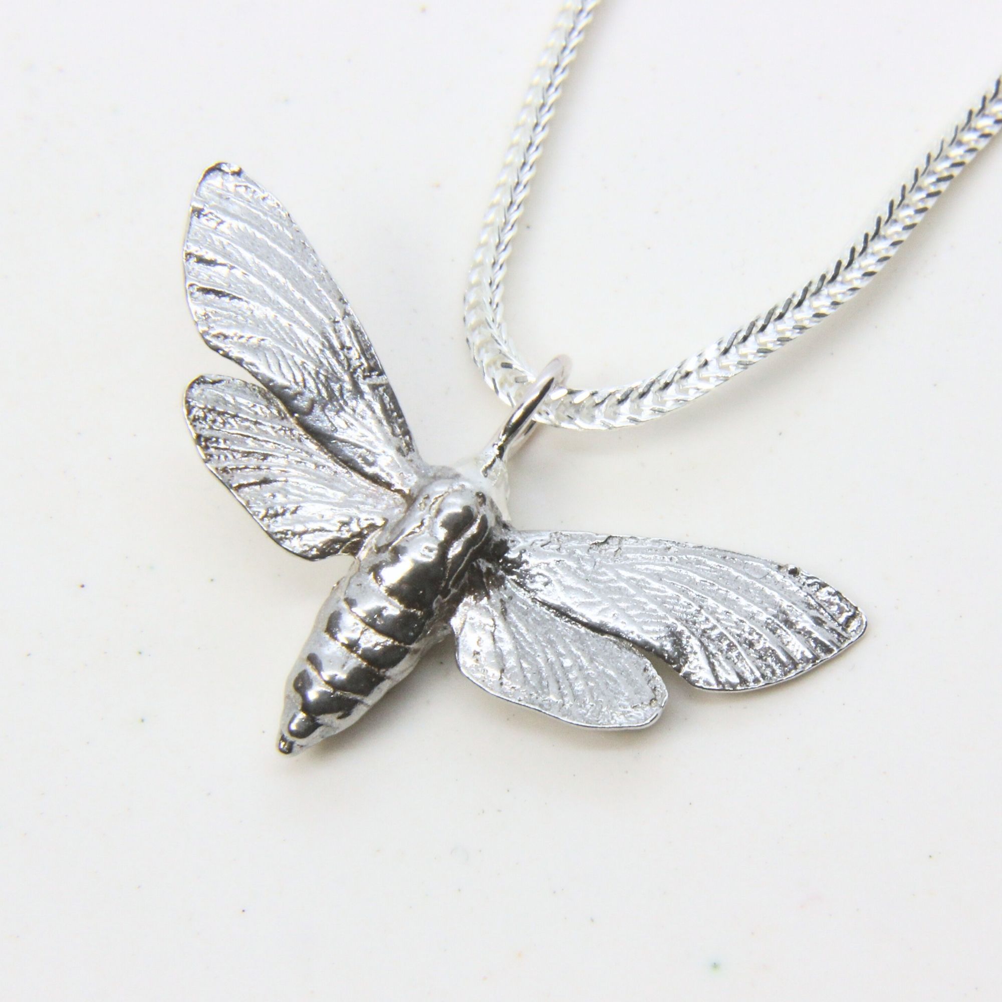 Sterling silver bee pendant with detailed wings and body on a silver chain.