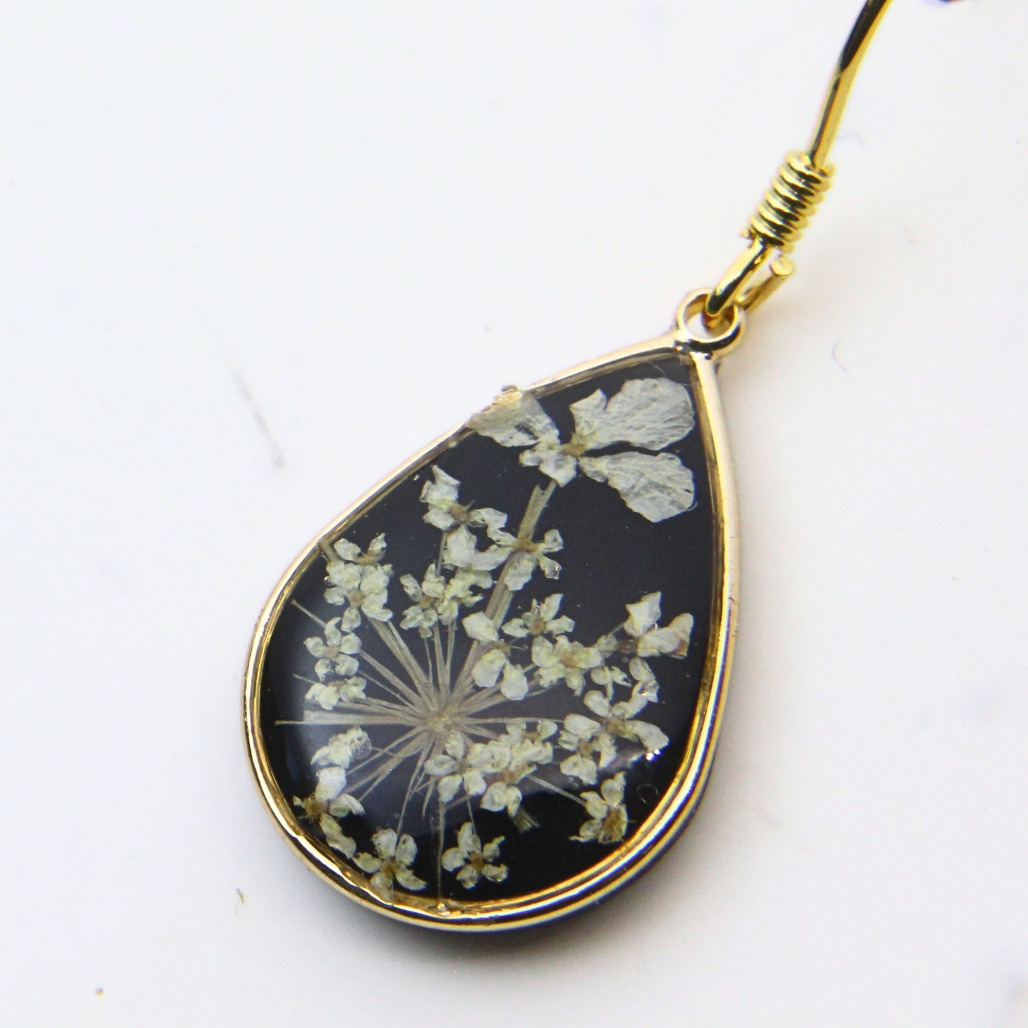 Gold plated drop earrings with lace flowers set in black resin.