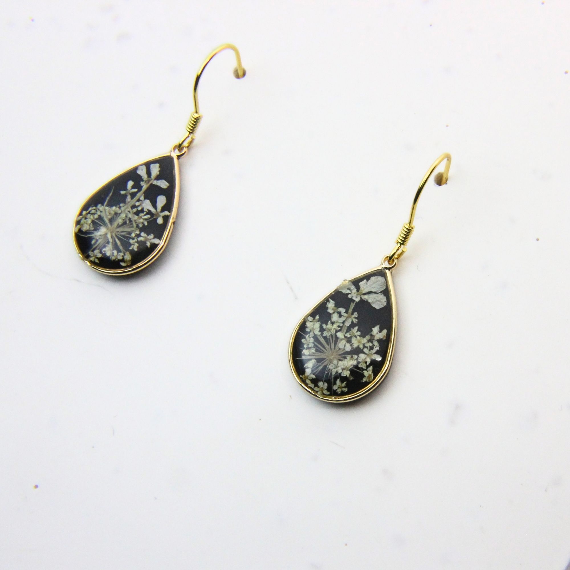 Gold plated drop earrings with lace flowers set in black resin.