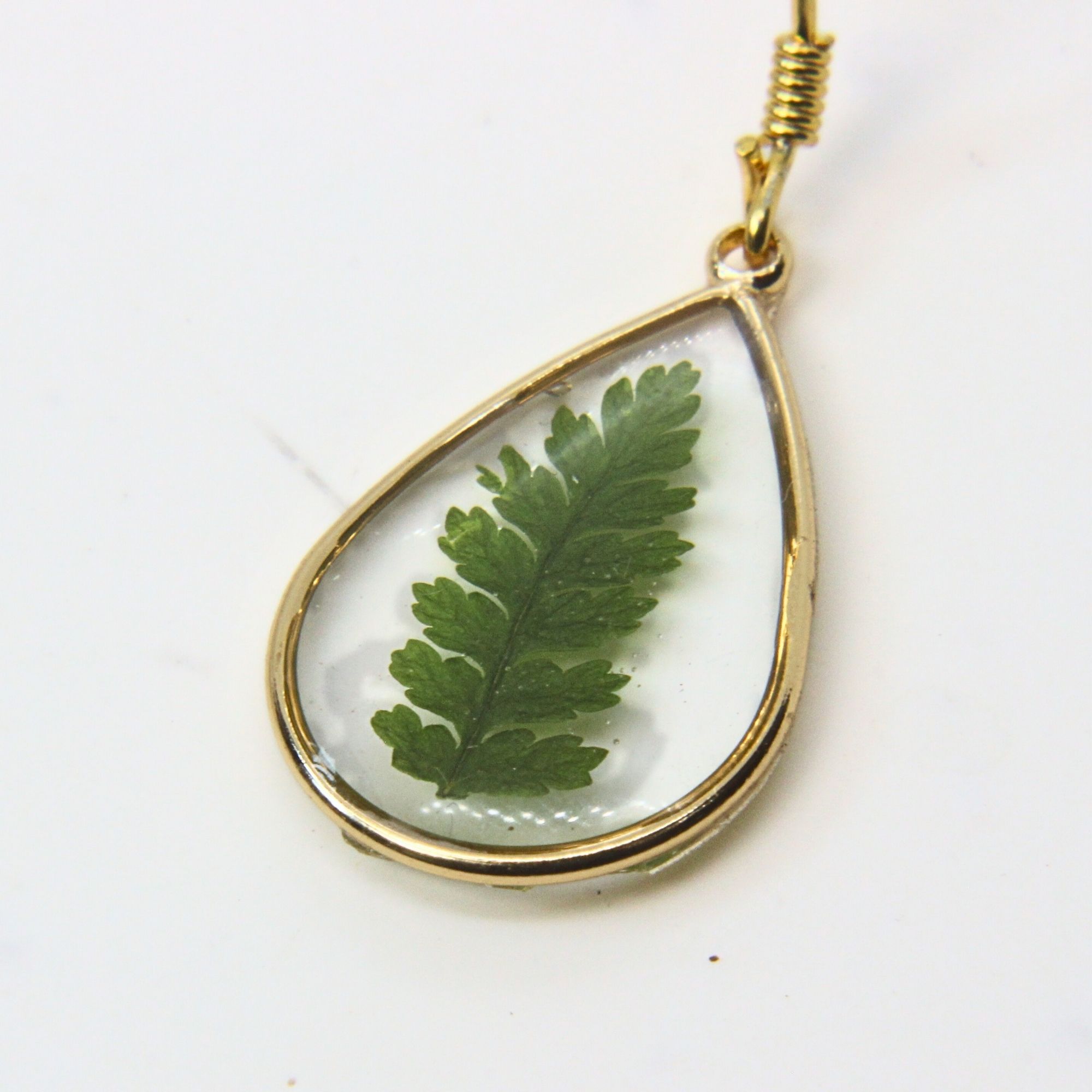 Gold teardrop earrings with real fern leaves preserved in resin.