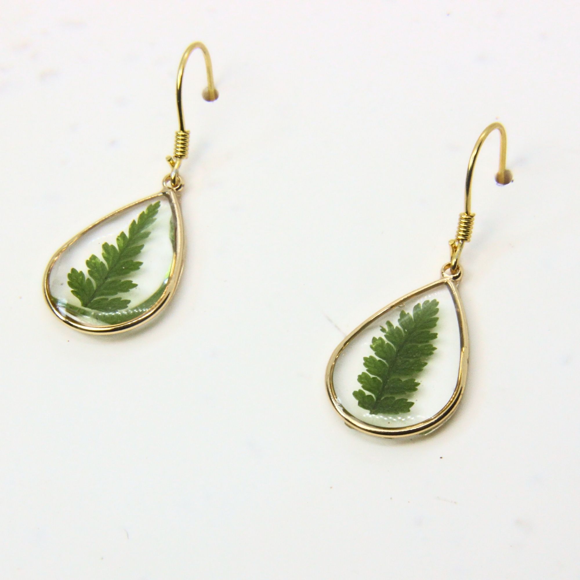 Gold teardrop earrings with real fern leaves preserved in resin.
