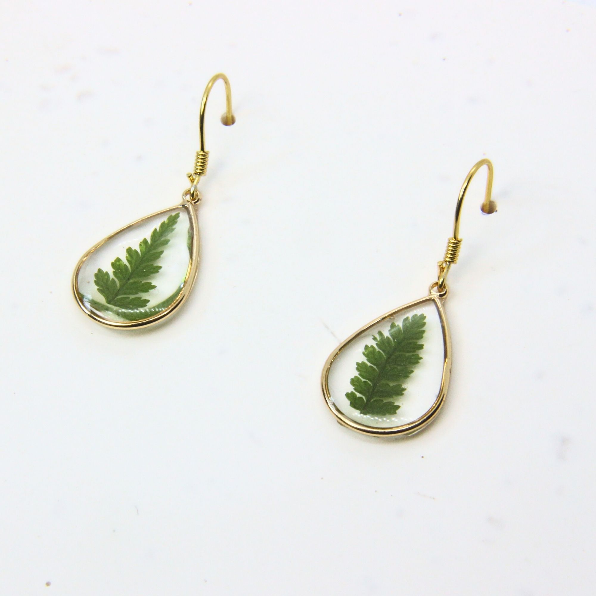 Gold teardrop earrings with real fern leaves preserved in resin.
