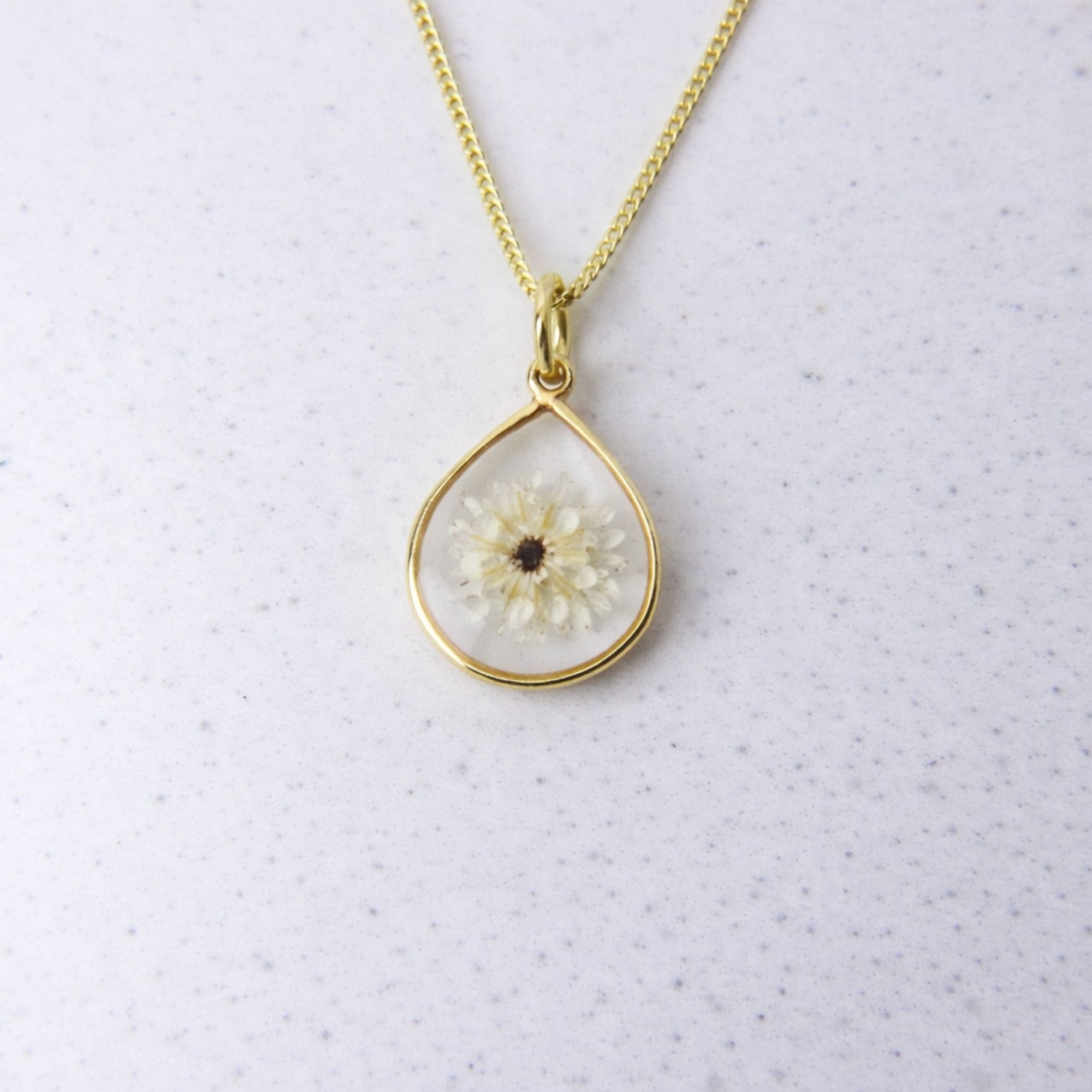 Gold teardrop pendant with a preserved white fynbos flower set in clear resin on a gold chain.